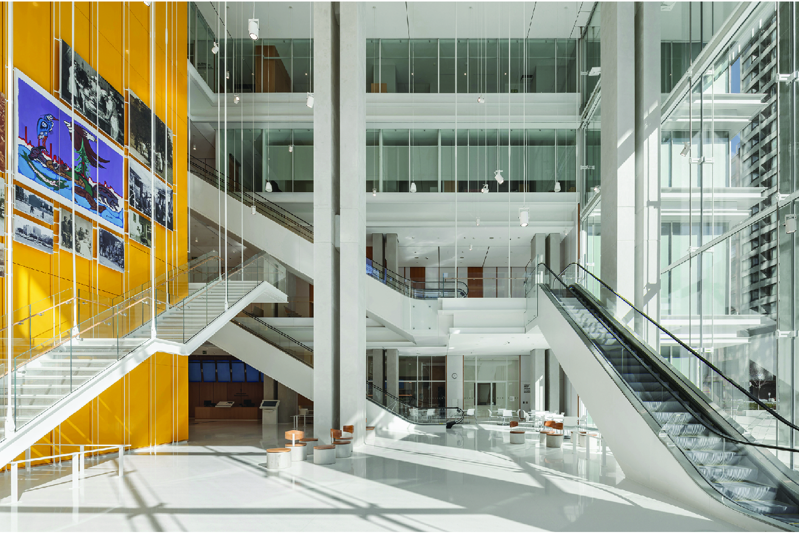 Atrium interior servicing high traffic public floors with yellow quartz clad elevator core and feature images